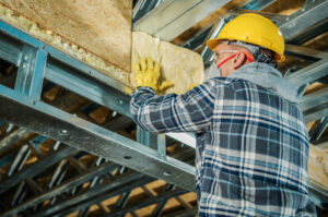 Caucasian Construction Worker in His 40s Insulating Building Ceiling with Mineral Wool Insulating Material.