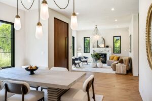 Modern open-plan living and dining area with stylish decor, wooden floors, and large windows offering natural light.